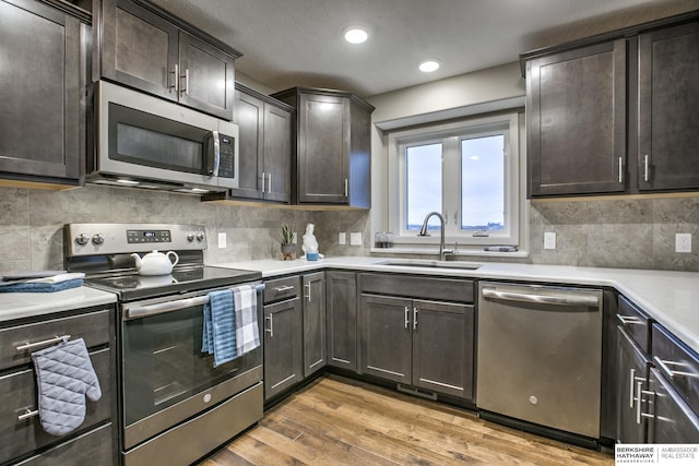 kitchen featuring tasteful backsplash, dark brown cabinetry, stainless steel appliances, sink, and hardwood / wood-style flooring