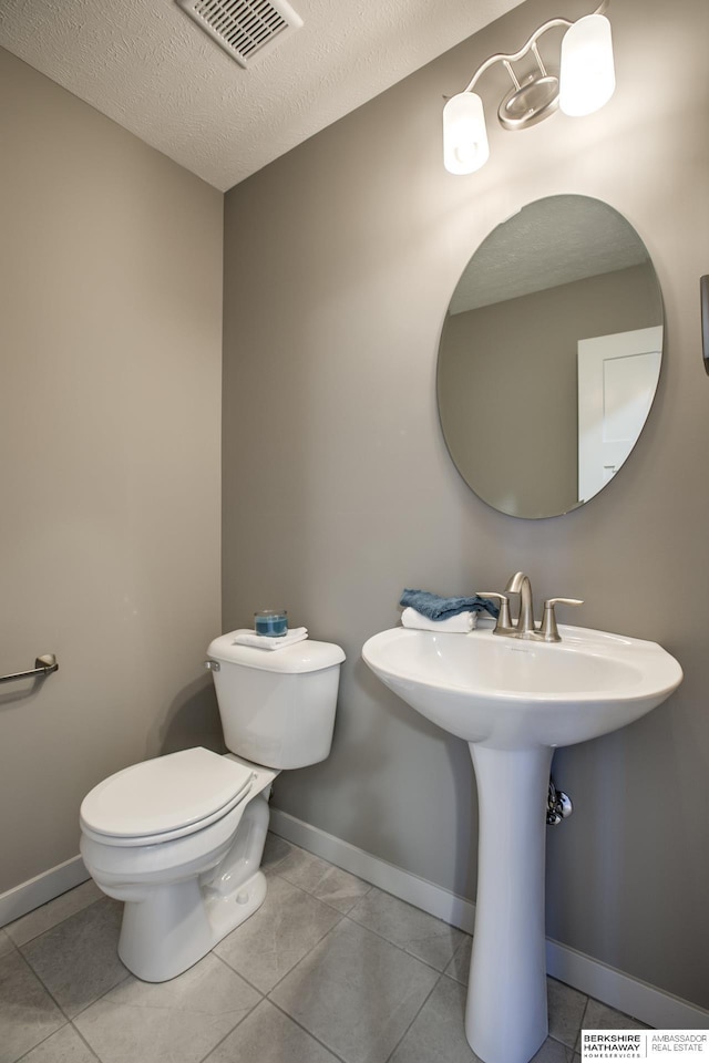 bathroom featuring tile patterned floors, toilet, and a textured ceiling