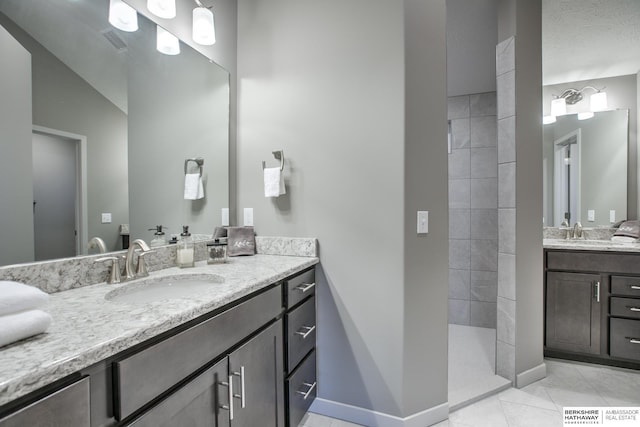 bathroom with a tile shower, tile patterned flooring, vanity, and lofted ceiling