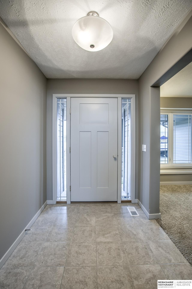 carpeted entryway with a textured ceiling