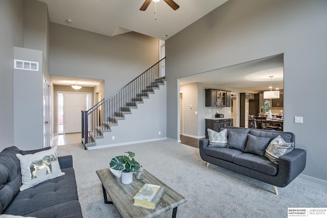 carpeted living room with ceiling fan and a towering ceiling