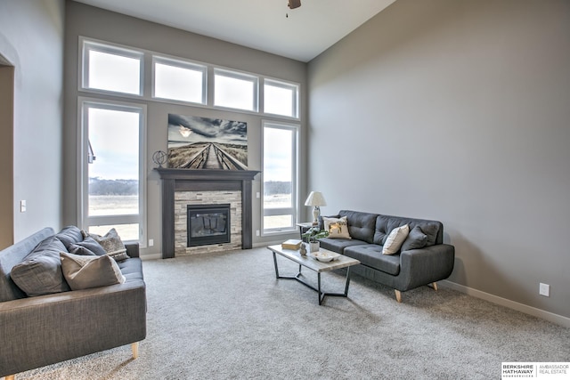 living room with carpet flooring, ceiling fan, a stone fireplace, and high vaulted ceiling