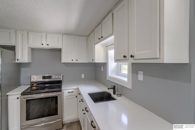 kitchen with white cabinets, electric stove, sink, a textured ceiling, and light hardwood / wood-style floors