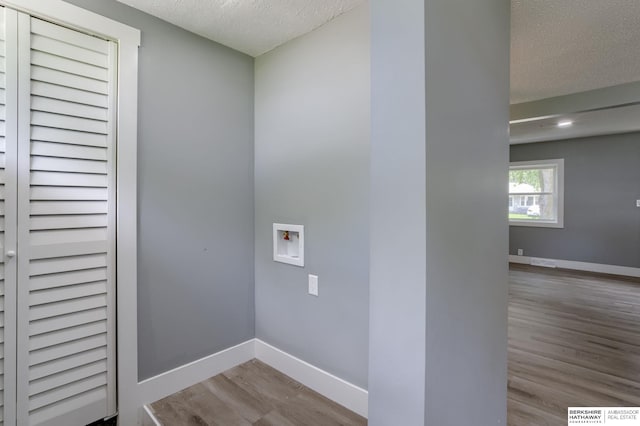 clothes washing area featuring hookup for a washing machine, a textured ceiling, and light hardwood / wood-style flooring