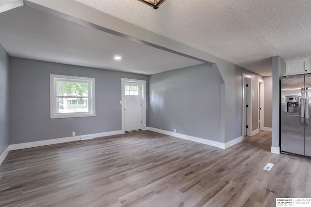 unfurnished living room featuring a textured ceiling and light hardwood / wood-style flooring