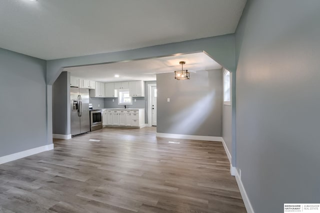 unfurnished living room with a notable chandelier, a healthy amount of sunlight, and light wood-type flooring