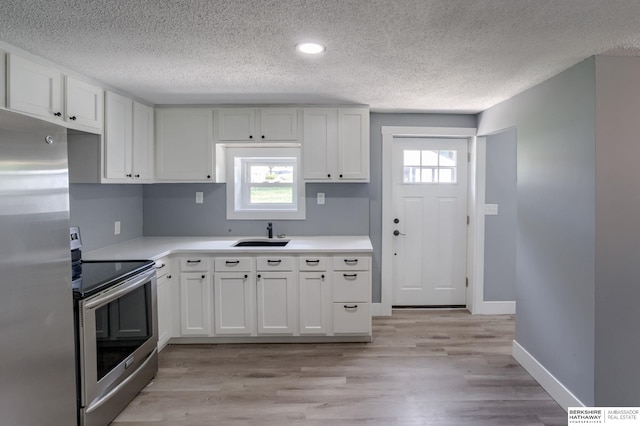 kitchen with appliances with stainless steel finishes, white cabinetry, and a wealth of natural light