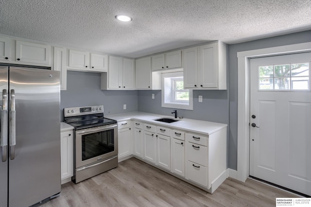 kitchen with a healthy amount of sunlight, white cabinetry, sink, and appliances with stainless steel finishes