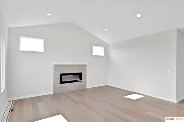 unfurnished living room with a healthy amount of sunlight, light hardwood / wood-style floors, vaulted ceiling, and a fireplace