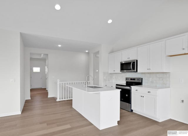 kitchen featuring sink, white cabinets, light wood-type flooring, an island with sink, and appliances with stainless steel finishes