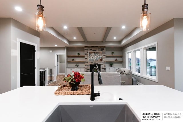 kitchen with sink, built in features, beamed ceiling, decorative light fixtures, and a fireplace