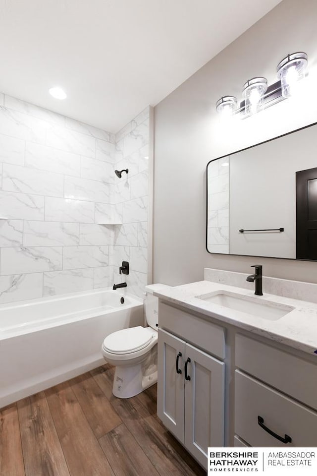 full bathroom with hardwood / wood-style floors, vanity, toilet, and tiled shower / bath