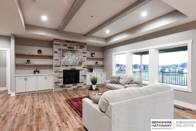 living room featuring light wood-type flooring and a stone fireplace