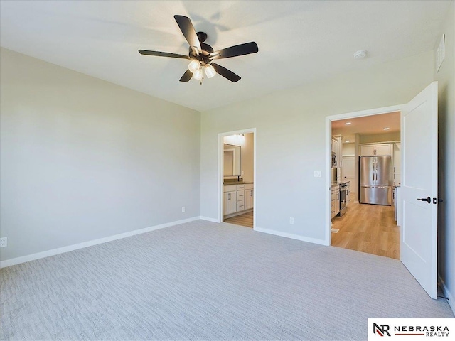 unfurnished bedroom with ceiling fan, light carpet, stainless steel refrigerator, and connected bathroom