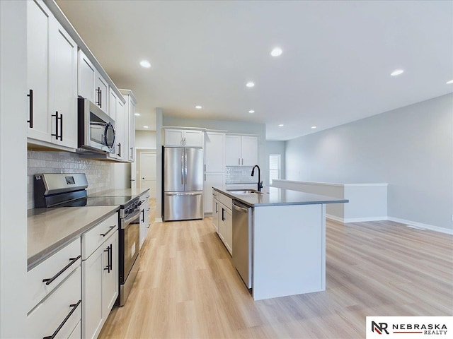 kitchen with white cabinetry, a kitchen island with sink, sink, and stainless steel appliances