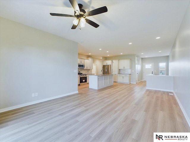 unfurnished living room featuring ceiling fan, light hardwood / wood-style floors, and sink