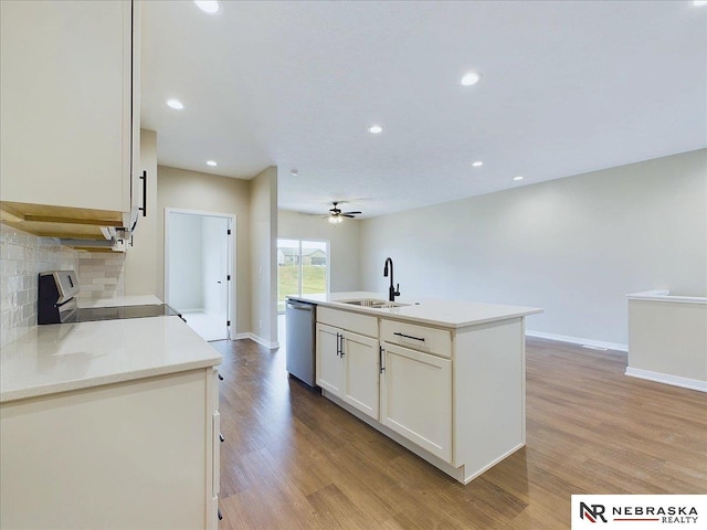 kitchen featuring sink, dishwasher, range, light hardwood / wood-style floors, and an island with sink