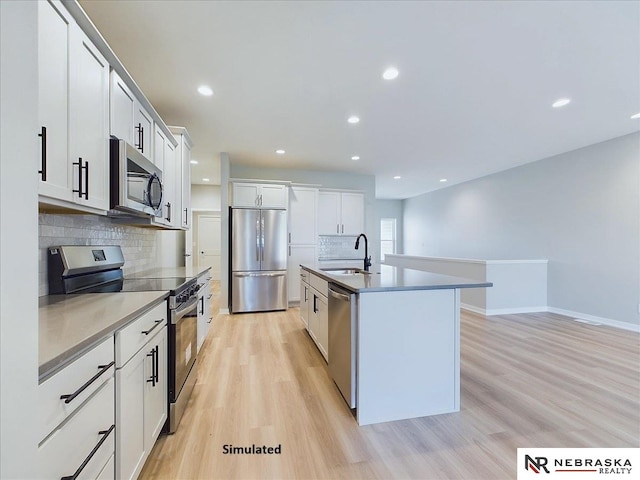 kitchen with a center island with sink, white cabinetry, sink, and appliances with stainless steel finishes