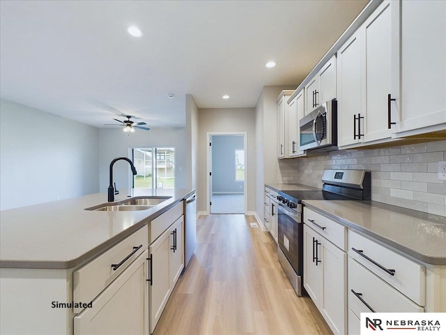 kitchen featuring a kitchen island with sink, white cabinets, sink, ceiling fan, and appliances with stainless steel finishes