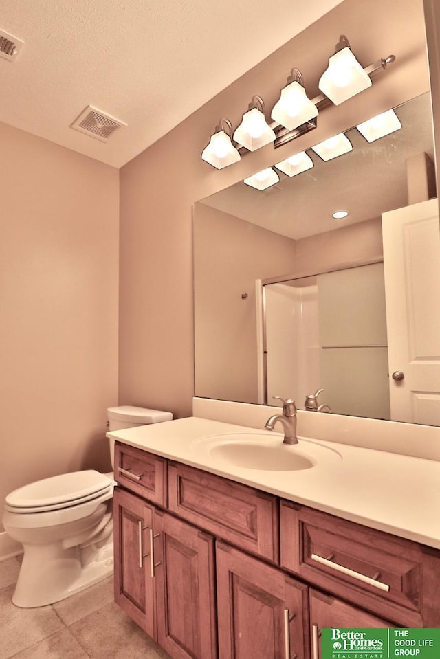 bathroom with toilet, vanity, tile patterned floors, and a shower with shower door