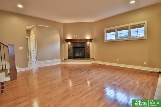 unfurnished living room featuring a tile fireplace and light hardwood / wood-style flooring