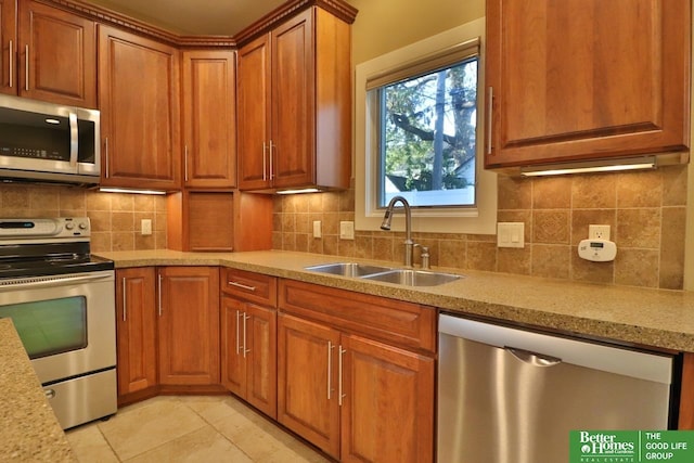 kitchen featuring sink, tasteful backsplash, light stone counters, light tile patterned flooring, and appliances with stainless steel finishes