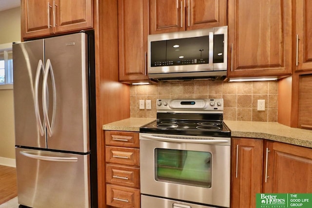 kitchen featuring decorative backsplash, light stone counters, and appliances with stainless steel finishes