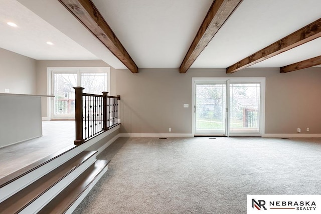 carpeted spare room with beamed ceiling and a healthy amount of sunlight