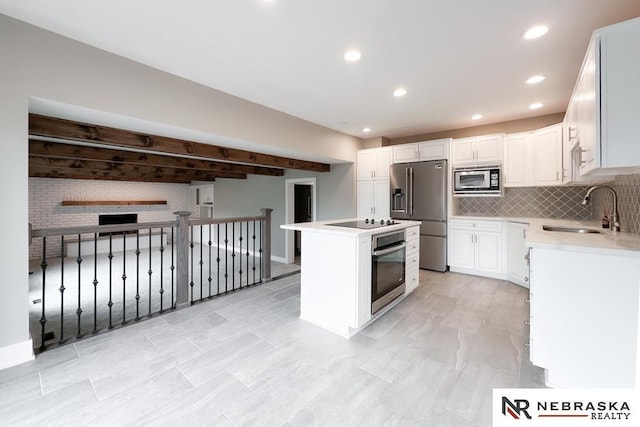 kitchen featuring white cabinetry, sink, a center island, stainless steel appliances, and backsplash