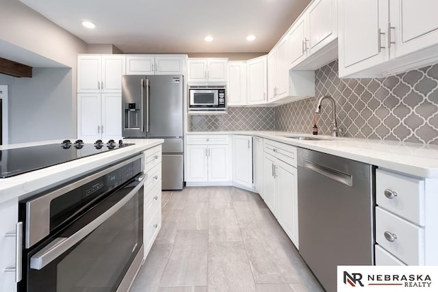 kitchen with decorative backsplash, white cabinetry, sink, and appliances with stainless steel finishes