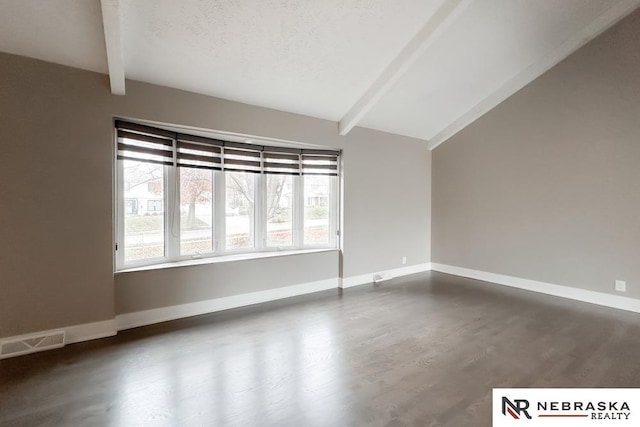 spare room with vaulted ceiling with beams, dark wood-type flooring, and a textured ceiling