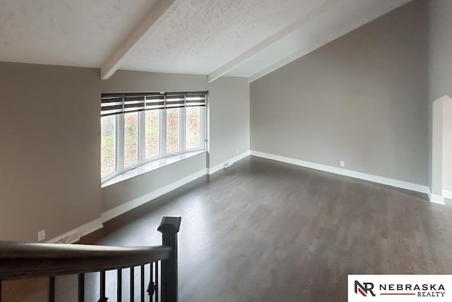 interior space with a textured ceiling, vaulted ceiling with beams, and dark hardwood / wood-style floors