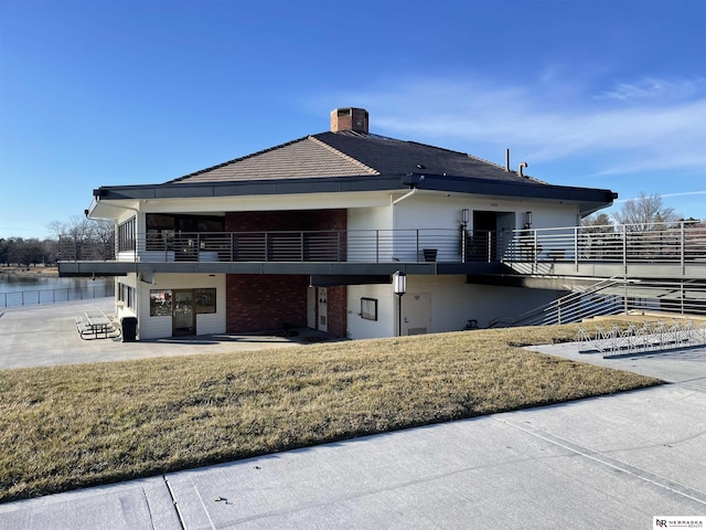 back of property featuring a lawn, a patio area, a water view, and central AC