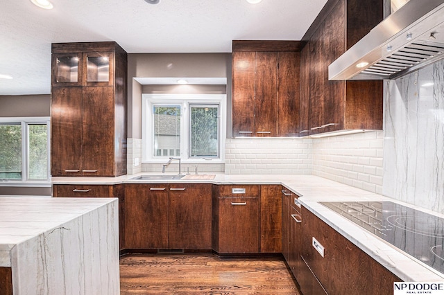 kitchen featuring decorative backsplash, wall chimney exhaust hood, black electric cooktop, dark wood-type flooring, and sink