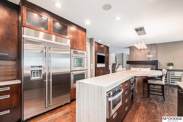 kitchen featuring beverage cooler, stainless steel appliances, a kitchen breakfast bar, dark hardwood / wood-style flooring, and a kitchen island