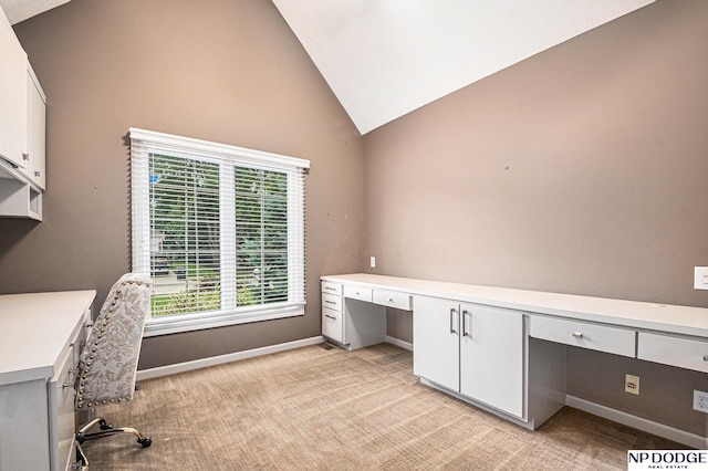 carpeted office with built in desk and lofted ceiling