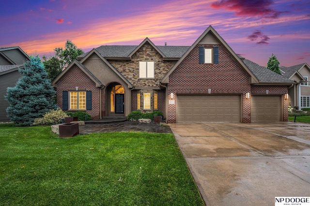 view of front of house featuring a garage, a lawn, concrete driveway, stone siding, and brick siding