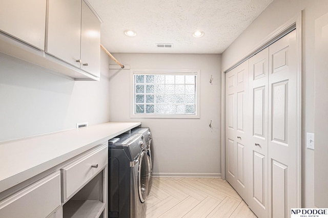 washroom with cabinets, separate washer and dryer, a textured ceiling, and light parquet flooring