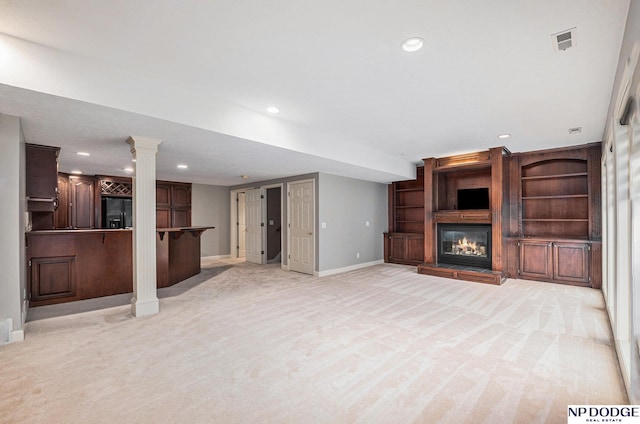 unfurnished living room featuring ornate columns and light carpet