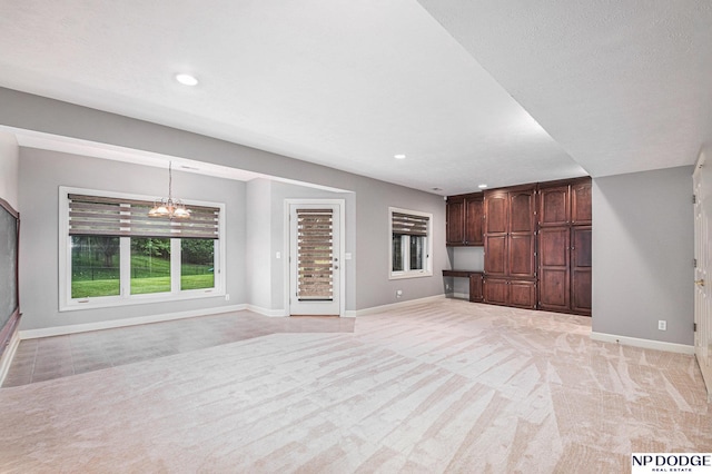 unfurnished living room with a chandelier and light colored carpet