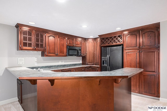 kitchen featuring a kitchen breakfast bar, kitchen peninsula, and black appliances