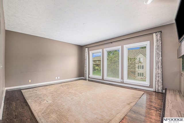 unfurnished room with dark hardwood / wood-style flooring and a textured ceiling