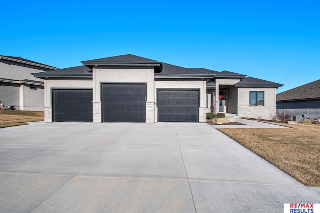 prairie-style home with central AC, a garage, and a front lawn