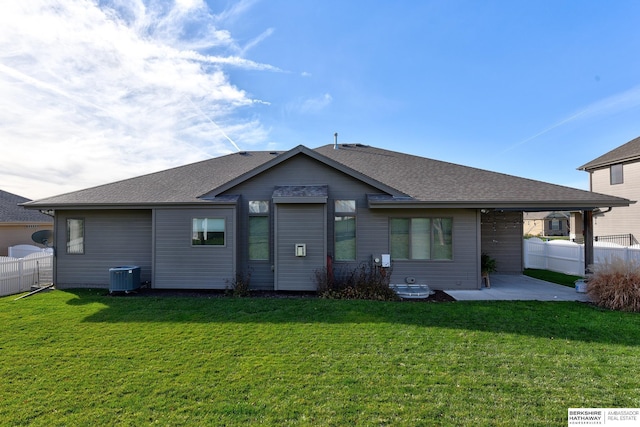 back of house featuring a lawn, central AC, fence, a shingled roof, and a patio area