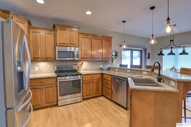 kitchen with a breakfast bar, sink, hanging light fixtures, kitchen peninsula, and stainless steel appliances