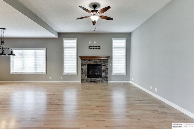 unfurnished living room featuring a fireplace, ceiling fan with notable chandelier, and light hardwood / wood-style flooring