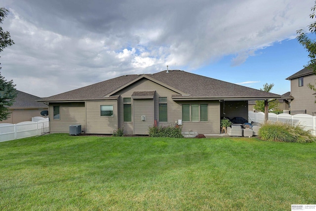 rear view of house with a lawn, central AC unit, a fenced backyard, and a shingled roof