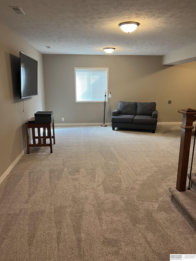 living room featuring visible vents, carpet floors, a textured ceiling, and baseboards