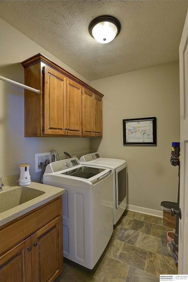 clothes washing area featuring sink, cabinets, a textured ceiling, and independent washer and dryer