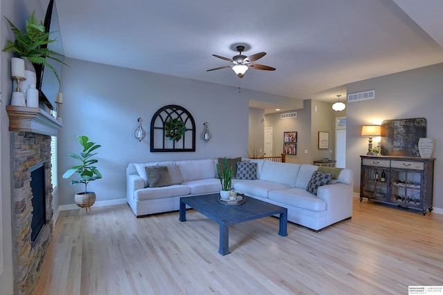 living room with ceiling fan, light wood-type flooring, and a fireplace